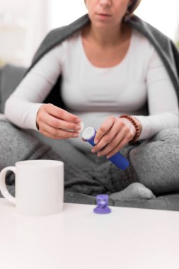 Hamile kadın bir bardak suda vitamin hapı alıyor..