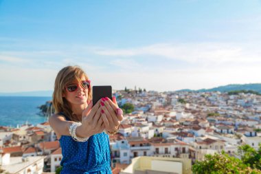 Güzel şehir panoramasının üstünde cep telefonu kullanan genç bir kadın..