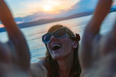 Güneşli bir sahilde selfie çeken gülümseyen kız..