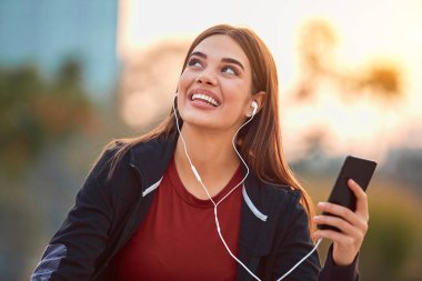 Cep telefonlu modern genç kadın koşu / egzersiz sırasında mola veriyor.