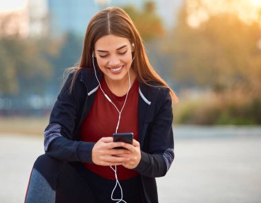 Cep telefonlu modern genç kadın koşu / egzersiz sırasında mola veriyor.