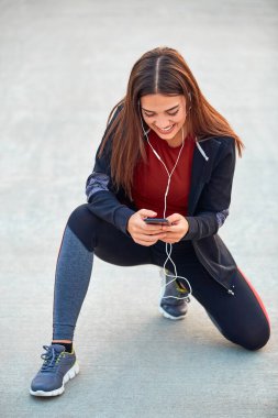 Cep telefonlu modern genç kadın koşu / egzersiz sırasında mola veriyor.