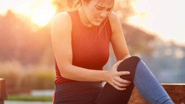 Young sportswoman having pain / injury during exercise and jogging in the park.