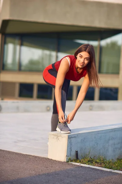 都市部の公園でランニングシューズを結ぶスポーティ女性 — ストック写真