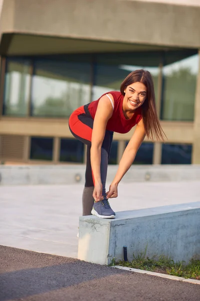 都市部の公園でランニングシューズを結ぶスポーティ女性 — ストック写真