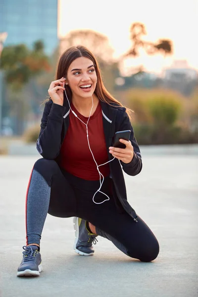 ジョギング 運動中に一時停止する携帯電話を持つ現代の若い女性 — ストック写真