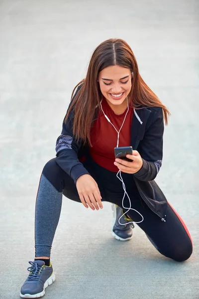 ジョギング 運動中に一時停止する携帯電話を持つ現代の若い女性 — ストック写真