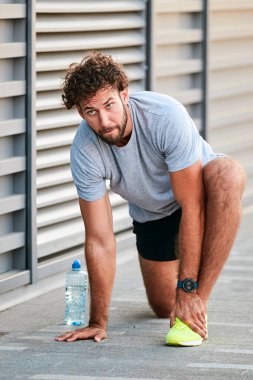 Genç adam kentsel alanda egzersiz yapıyor / esniyor.