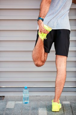 Genç adam kentsel alanda egzersiz yapıyor / esniyor.