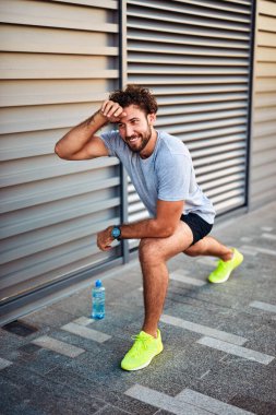 Genç adam kentsel alanda egzersiz yapıyor / esniyor.