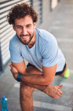 Genç adam kentsel alanda egzersiz yapıyor / esniyor.
