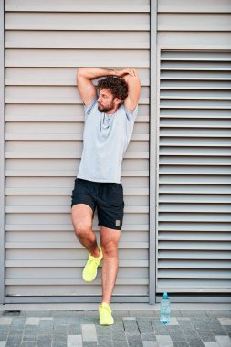 Genç adam kentsel alanda egzersiz yapıyor / esniyor.