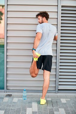 Genç adam kentsel alanda egzersiz yapıyor / esniyor.