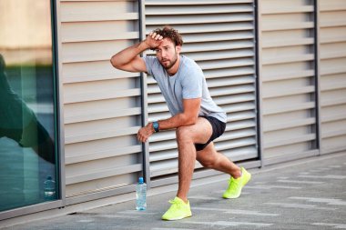 Genç adam kentsel alanda egzersiz yapıyor / esniyor.