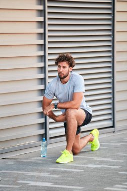 Genç adam kentsel alanda egzersiz yapıyor / esniyor.