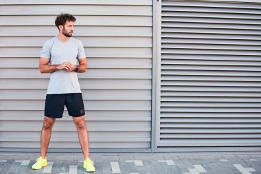 Genç adam kentsel alanda egzersiz yapıyor / esniyor.