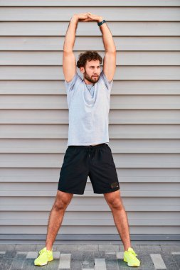 Genç adam kentsel alanda egzersiz yapıyor / esniyor.