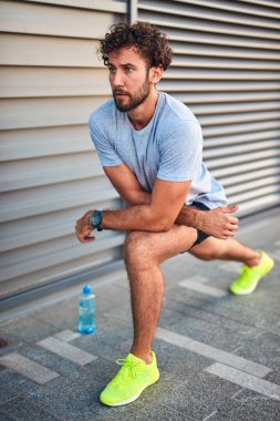 Genç adam kentsel alanda egzersiz yapıyor / esniyor.