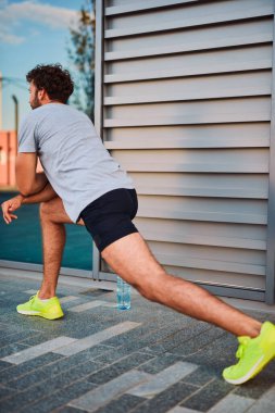 Genç adam kentsel alanda egzersiz yapıyor / esniyor.