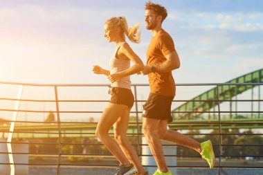 Nehir kenarındaki kentsel çevrede koşan / egzersiz yapan modern kadın ve erkek.