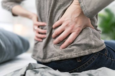 Yatakta uyanan kadın, sabah esnemesi, sırt ve kalça ağrısı..