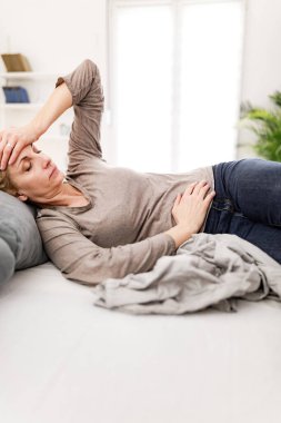 Evde mide sorunları olan yorgun bir kadın. Kanepede hasta ve hamile..