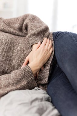 Evde mide sorunları olan yorgun bir kadın. Kanepede hasta ve hamile..