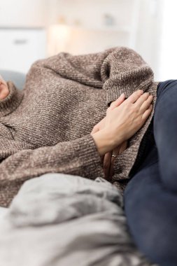 Evde mide sorunları olan yorgun bir kadın. Kanepede hasta ve hamile..