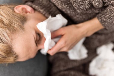 Yatakta hasta bir kadın, grip ve virüs enfeksiyonları, alerji, mevsimsel sağlık sorunları.