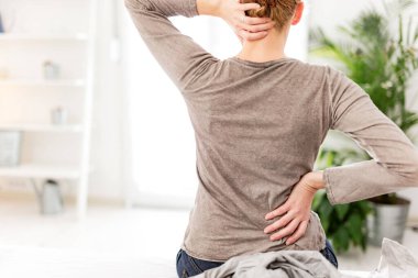 Kadın yatakta uyanıyor, sabah esniyor, sırtı ve boynu ağrıyor..