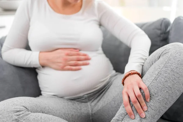 妊娠中の疲れ果てた女性胃 痛みの問題を自宅でソファの上に 病気であること — ストック写真