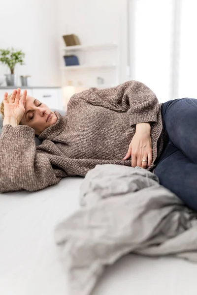 Evde mide sorunları olan yorgun bir kadın. Kanepede hasta ve hamile..