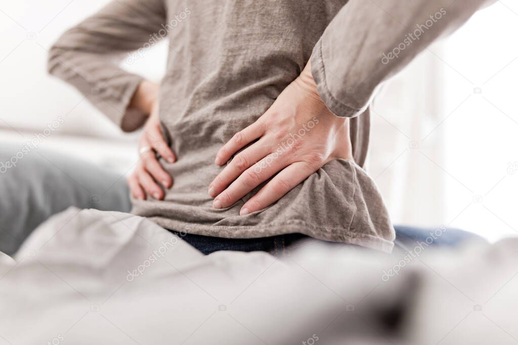 Woman waking up on the bed, morning stretching, pain in the back and hip.