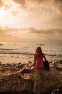 Kumsaldan uzak deniz manzarasına bakan bir kadın..