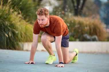 Genç modern adam şehir parkında koşuyor / egzersiz yapıyor.