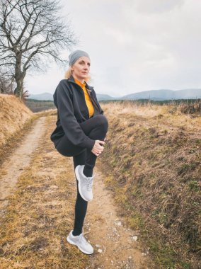 Yetişkin bir kadın doğada bir dağ yolunda koşuyor / egzersiz yapıyor.
