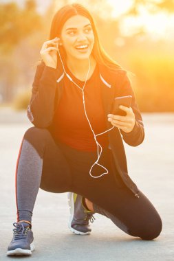 Cep telefonlu modern genç kadın koşu / egzersiz sırasında mola veriyor.