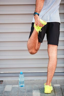 Genç adam kentsel alanda egzersiz yapıyor / esniyor.