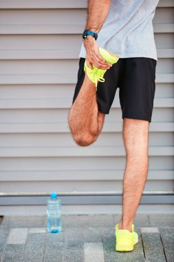 Genç adam kentsel alanda egzersiz yapıyor / esniyor.