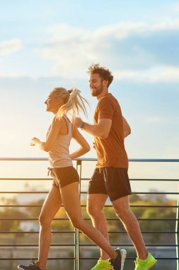 Nehir kenarındaki kentsel çevrede koşan / egzersiz yapan modern kadın ve erkek.