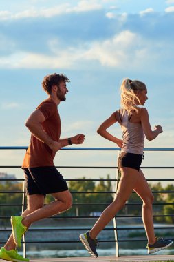 Nehir kenarındaki kentsel çevrede koşan / egzersiz yapan modern kadın ve erkek.