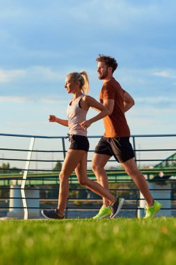 Nehir kenarındaki kentsel çevrede koşan / egzersiz yapan modern kadın ve erkek.