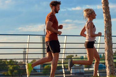 Nehir kenarındaki kentsel çevrede koşan / egzersiz yapan modern kadın ve erkek.