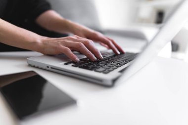 Dizüstü bilgisayar kullanan ve klavyede yazan kişi.