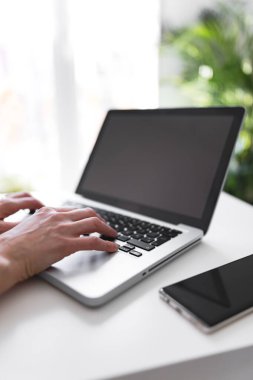 Dizüstü bilgisayar kullanan ve klavyede yazan kişi.