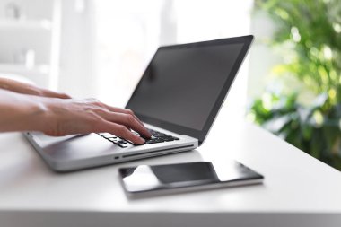 Dizüstü bilgisayar kullanan ve klavyede yazan kişi.