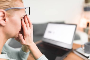 Kadın kendini iyi hissetmiyor, dizüstü bilgisayarla uğraşırken başı ağrıyor..