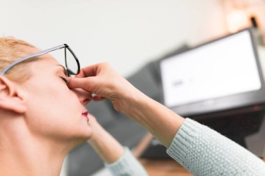 Kadın kendini iyi hissetmiyor, dizüstü bilgisayarla uğraşırken başı ağrıyor..