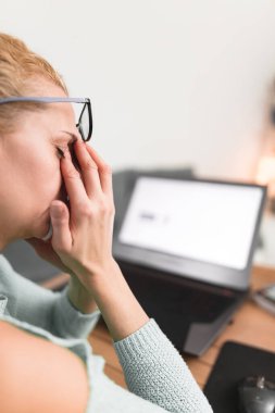 Kadın kendini iyi hissetmiyor, dizüstü bilgisayarla uğraşırken başı ağrıyor..