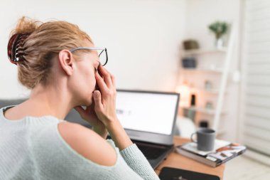 Kadın kendini iyi hissetmiyor, dizüstü bilgisayarla uğraşırken başı ağrıyor..